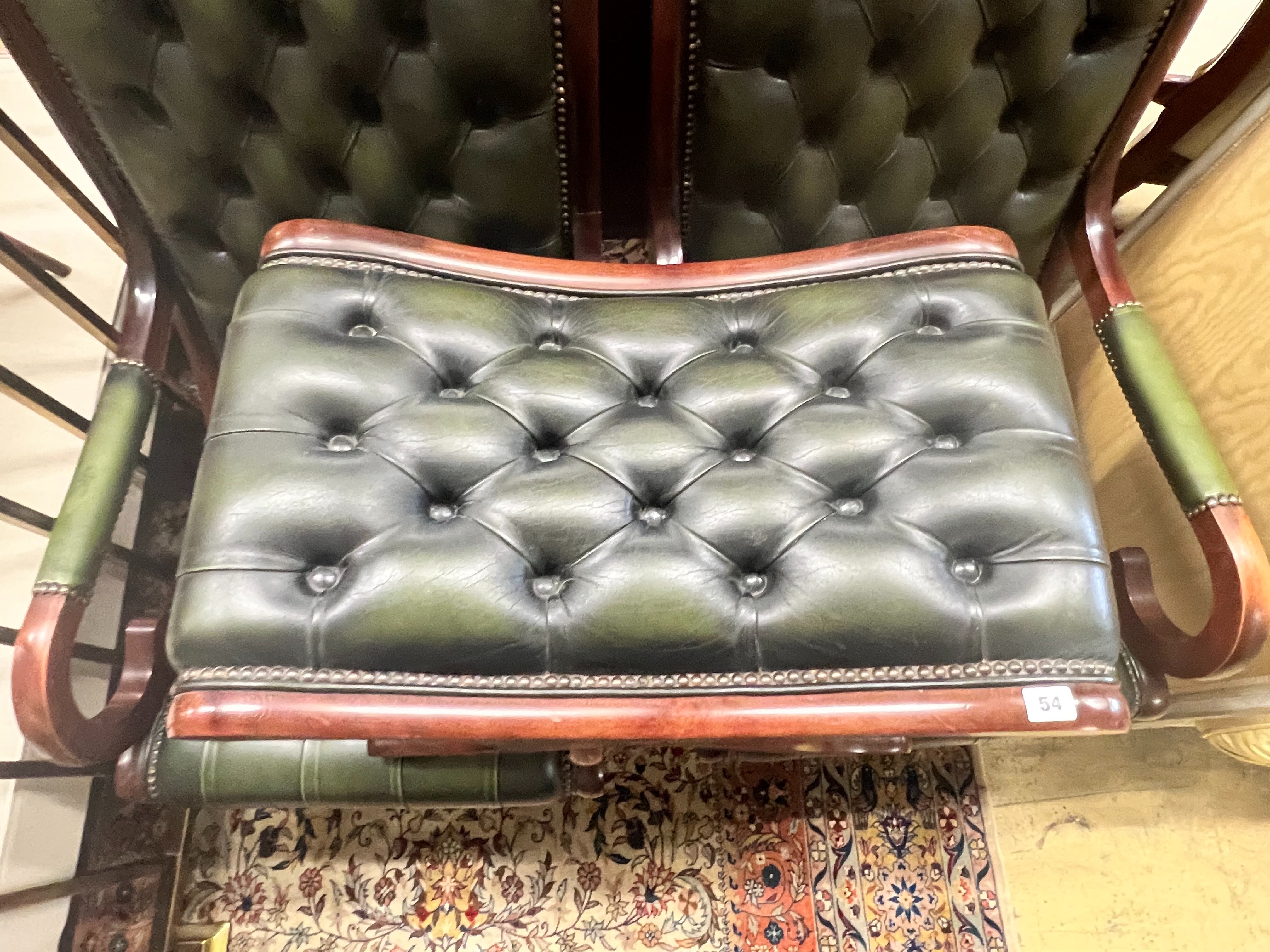 A pair of Victorian style mahogany and buttoned green leather open armchairs and matching footstool